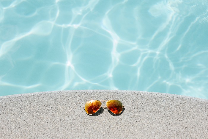 occhiali da sole su bordo piscina